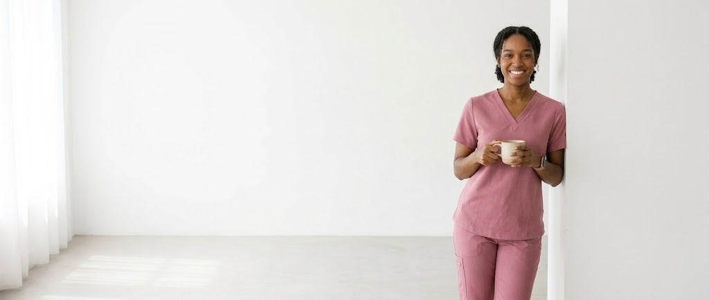 Healthcare worker in pink scrubs with a coffee